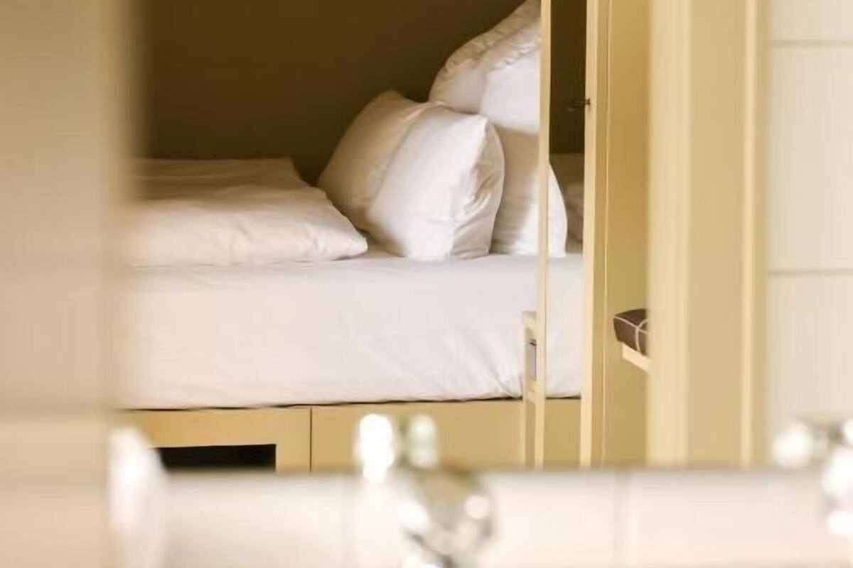 A hotel room with a bed, a bathroom with a sink, and a mirror reflecting the room.