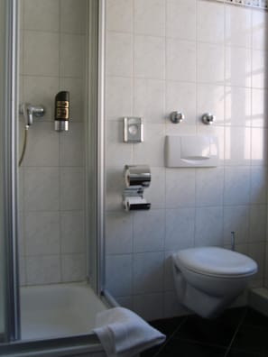 A bathroom with a shower, toilet, and towel rack. - Hotel Vier Jahreszeiten (Heidelberg)