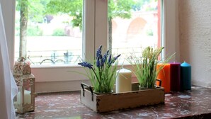 A window with a heart-shaped decoration, a candle, and a plant in a wooden box. - Hotel Vier Jahreszeiten (Heidelberg)
