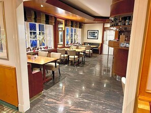 A restaurant with marble flooring, wooden tables, and chairs.