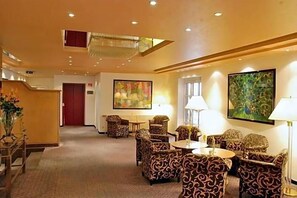 A hotel lobby with patterned armchairs, a reception desk, and artwork on the walls.