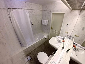 A bathroom with a bathtub, toilet, and two sinks.