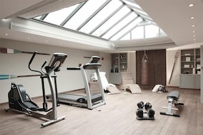 Un gimnasio moderno con equipo de ejercicio, tragaluces y vista al cielo.