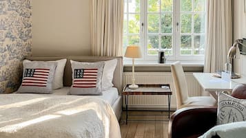 Ein Schlafzimmer mit einem Bett, einem Schreibtisch, einem Stuhl und einem Fenster mit Vorhängen.