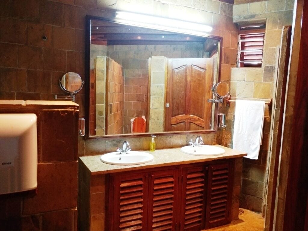 A bathroom with two sinks, wooden cabinets, a large mirror, and a towel rack.