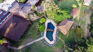 An aerial view of a resort with a swimming pool, multiple buildings, and well-maintained gardens.