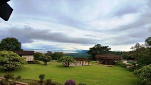 A landscaped garden with a gazebo, a lawn, and a view of distant hills.