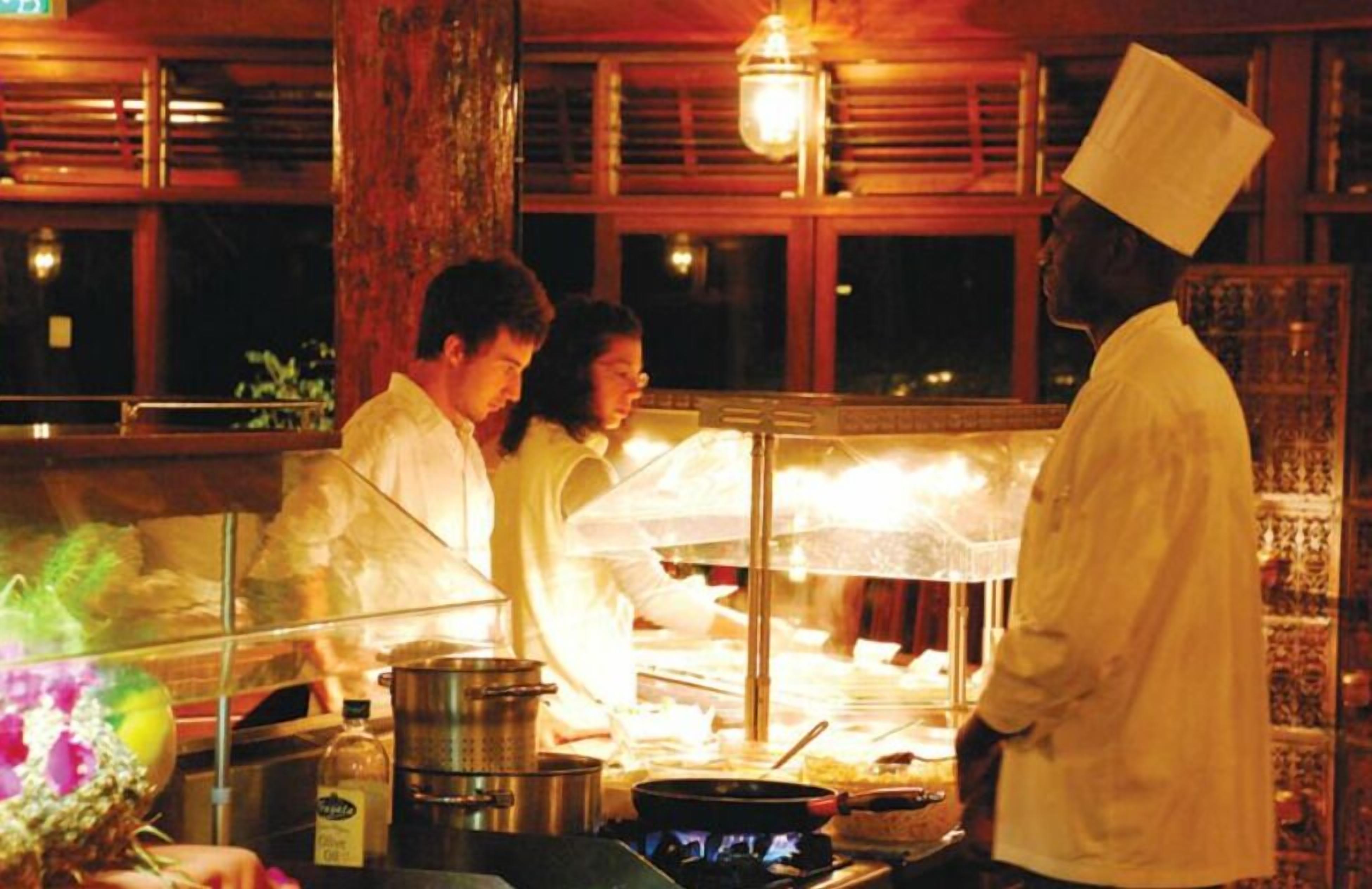 A kitchen with chefs working, a large stove, and cooking utensils.