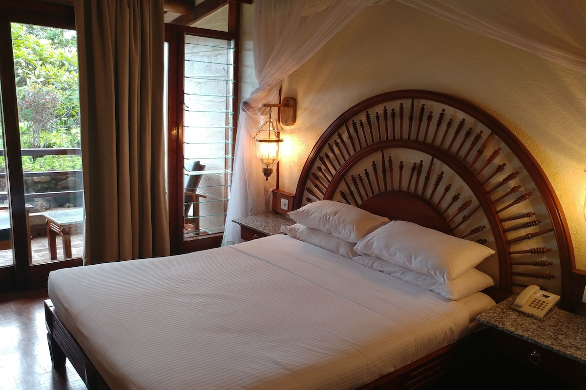 A neatly made bed with a wooden headboard, a bedside table with a lamp, and a phone.