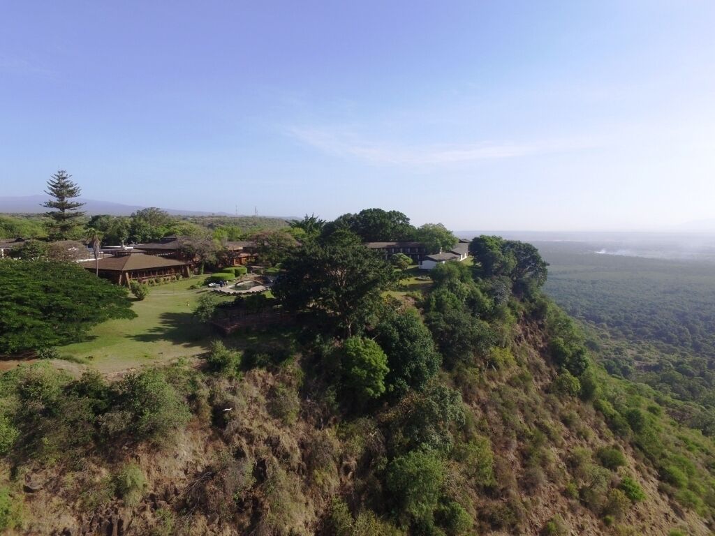 A resort with multiple buildings on a hillside, surrounded by dense greenery and overlooking a valley.