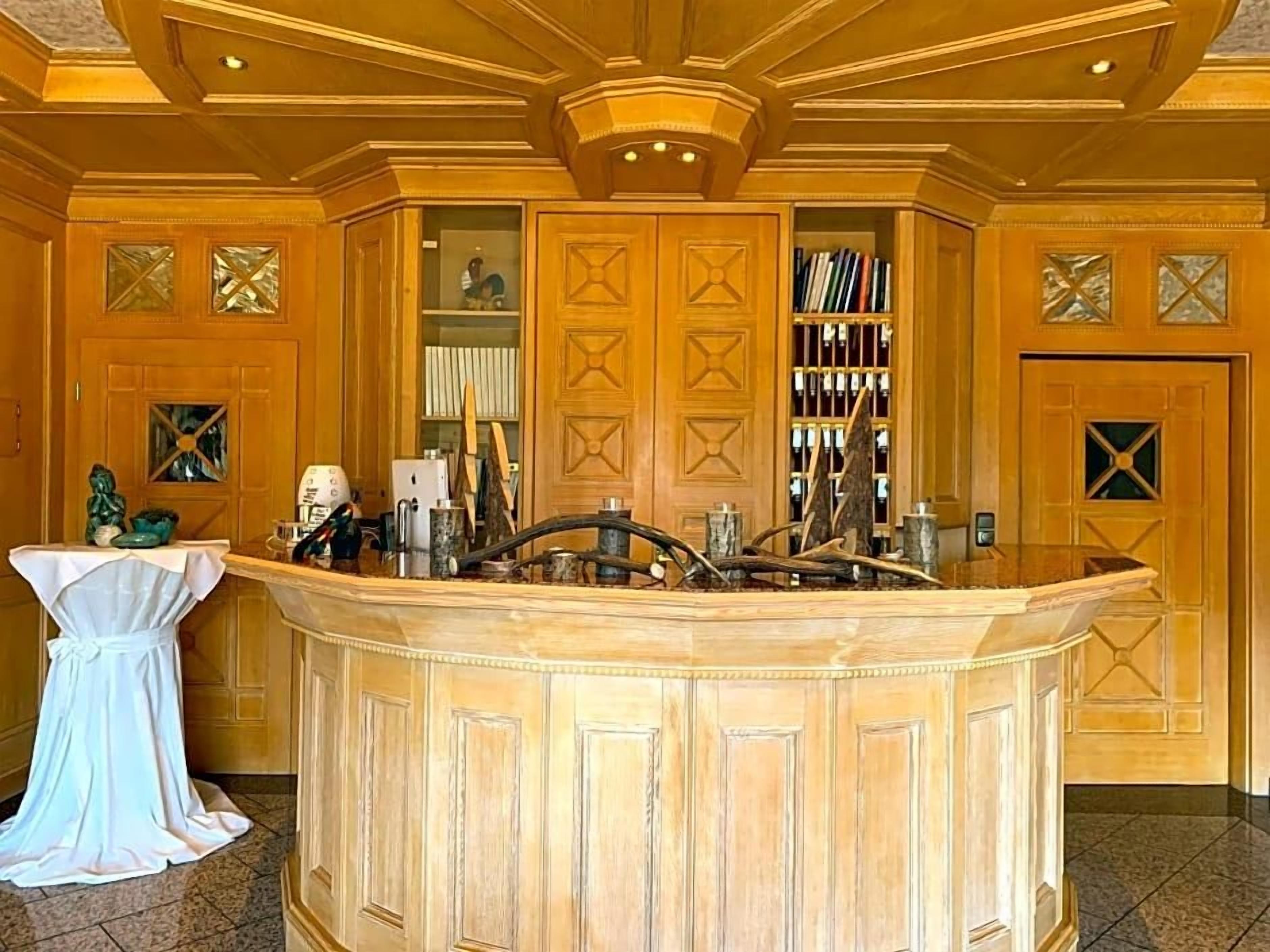 A reception area with a wooden reception desk, a white chair, and a bookshelf filled with books.
