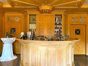 A reception area with a wooden reception desk, a white chair, and a bookshelf filled with books.