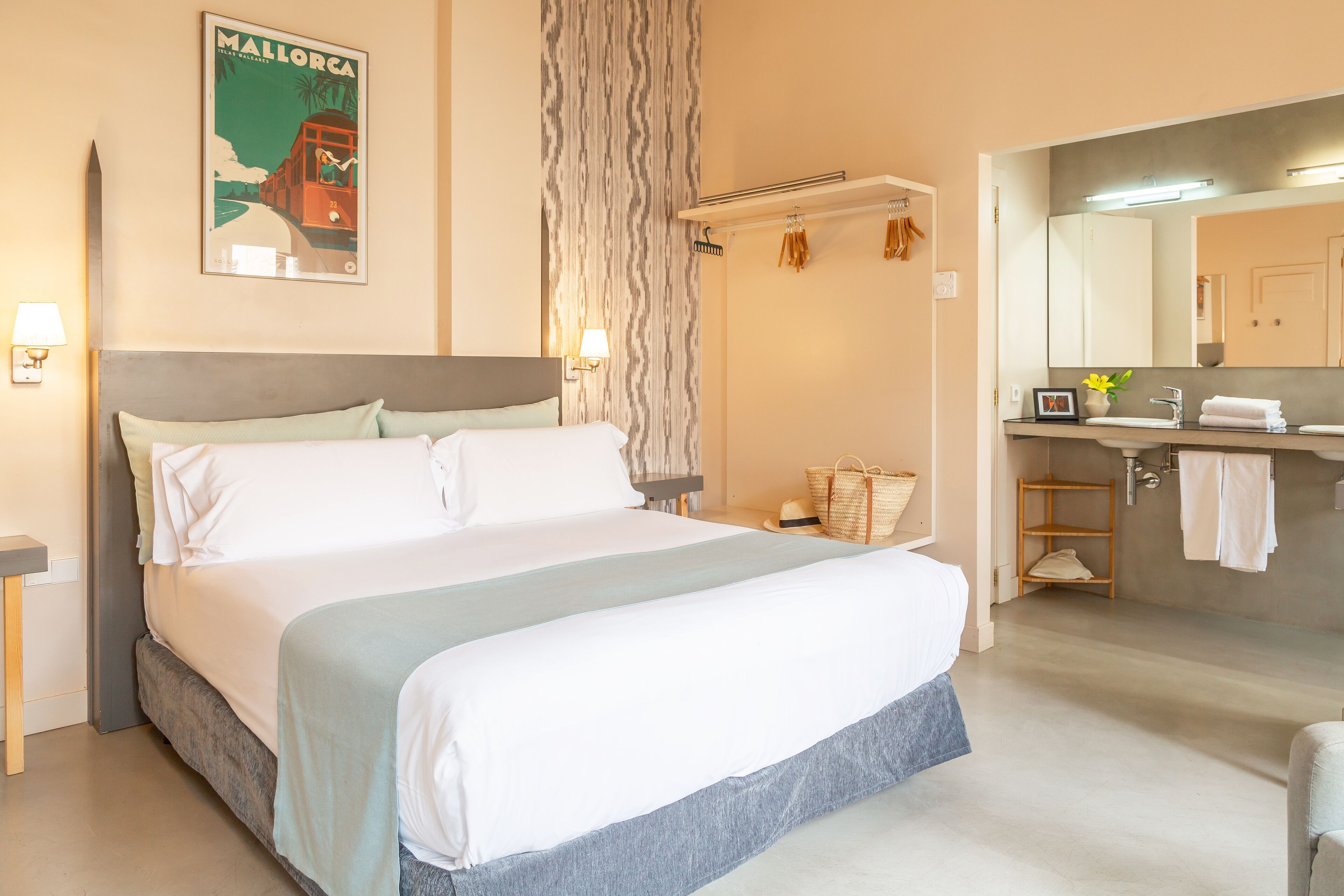 A hotel room with a large bed, a bathroom with a mirror, and a wall-mounted towel rack.
