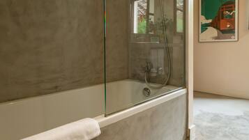 Un baño moderno con ducha de vidrio, bañera blanca y un perchero para toallas.