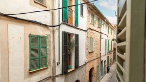 A narrow street with buildings featuring arched doorways and green shutters.