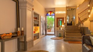 A spacious hallway with a staircase, a stained glass window, and a sign reading "@solleRooms".