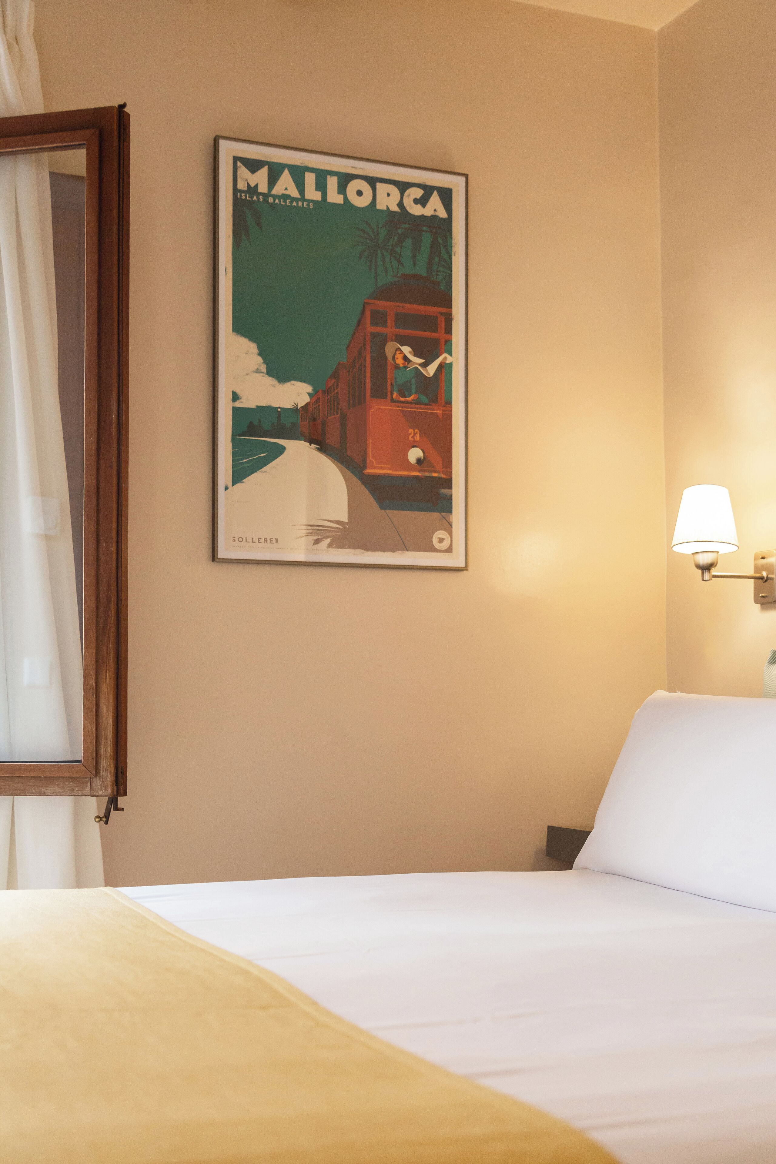 Habitación de hotel con una cama, una lámpara de pared y un cartel de Mallorca.