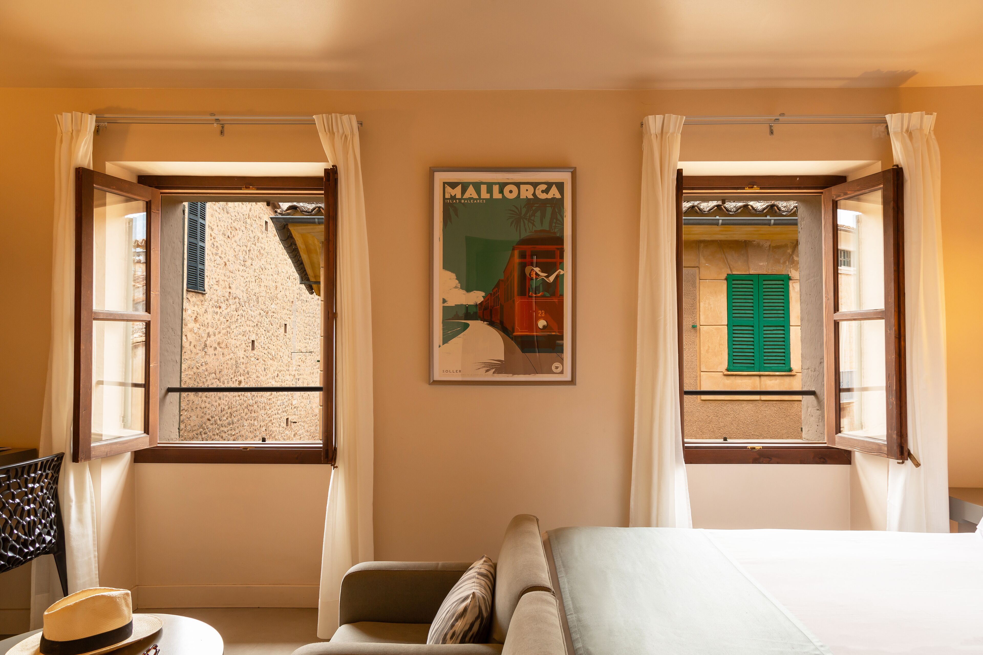 A bedroom with two windows, a bed, a chair, and a poster on the wall.
