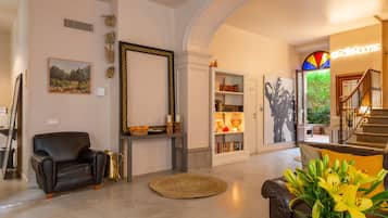 Amplia sala de estar con un sillón de cuero, una estantería y una escalera que lleva a un nivel superior.