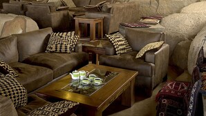 A cozy lounge area with leather sofas, patterned cushions, a wooden coffee table, and wall-mounted lanterns. - Seronera Wildlife Lodge (Serengeti)