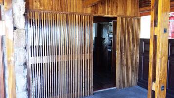 A wooden door with vertical slats, leading to a room with a tiled floor.
