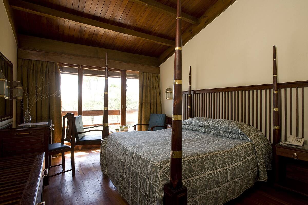 Une chambre à coucher avec un lit à baldaquin, des meubles en bois et une vue sur l’extérieur.