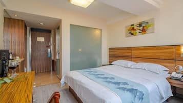 Una habitación de hotel con una cama, una mesita de noche y un escritorio con silla.
