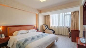 Habitación de hotel con una cama grande, un escritorio, una silla, una guitarra y un televisor.