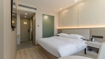 A hotel room with a bed, bedside table, and a mirror.