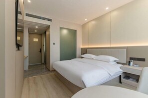 A hotel room with a bed, bedside table, and a mirror.