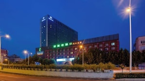 Um hotel moderno com fachada de vidro marcante e sinalização iluminada.