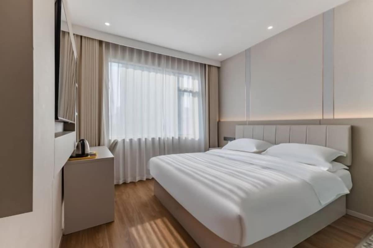 Un dormitorio moderno con una cama grande, una mesita de noche y una ventana con cortinas.