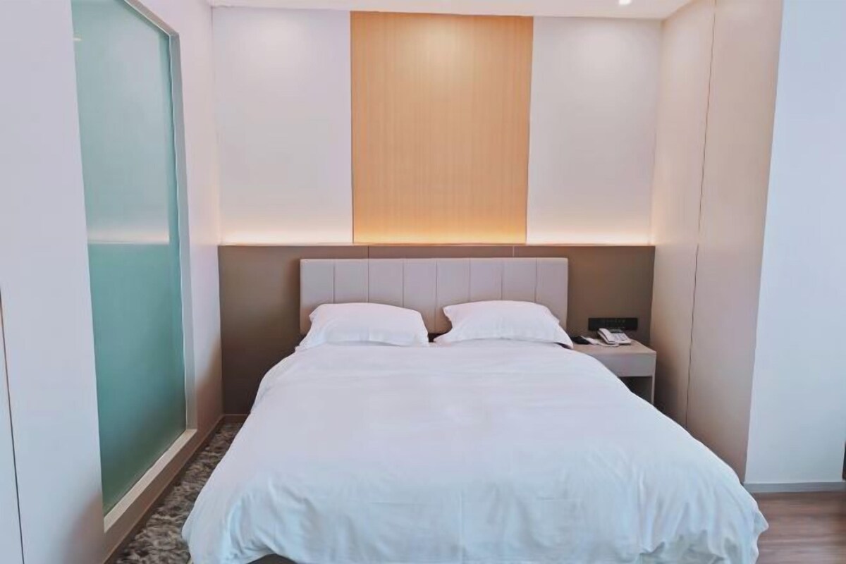 A hotel room with a bed, bedside table, and a nightstand.