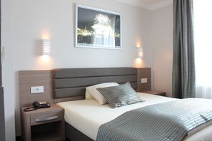 A hotel room with a bed, bedside tables, a telephone, and a framed picture on the wall.