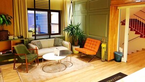 A modern living room with a sofa, chairs, a coffee table, and a potted plant. - St. Joseph Hotel (Hamburg)