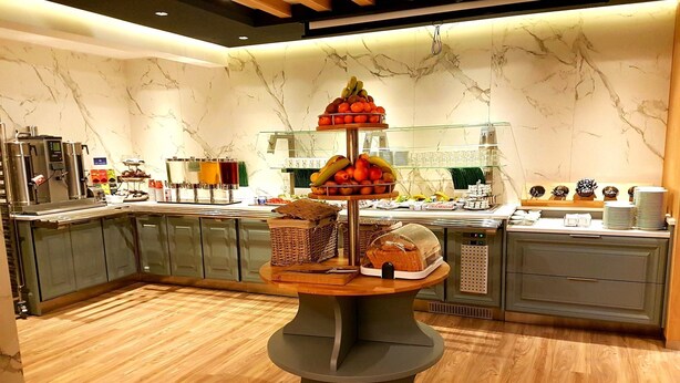 A buffet setup with a central serving table, glass display cases, and a marble wall background. - St. Joseph Hotel (Hamburg)