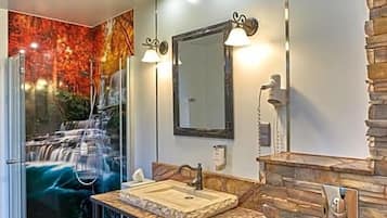 Een moderne badkamer met een glazen douche, een houten wastafelmeubel en een accentmuur van steen.