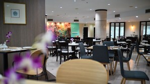 Un espace de restauration moderne, doté de plusieurs tables et chaises, d’un grand mur décoratif et d’un pilier central.