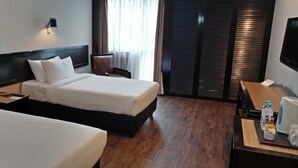 Une chambre d’hôtel avec deux lits, un bureau avec une chaise, une télévision et une fenêtre avec des rideaux.
