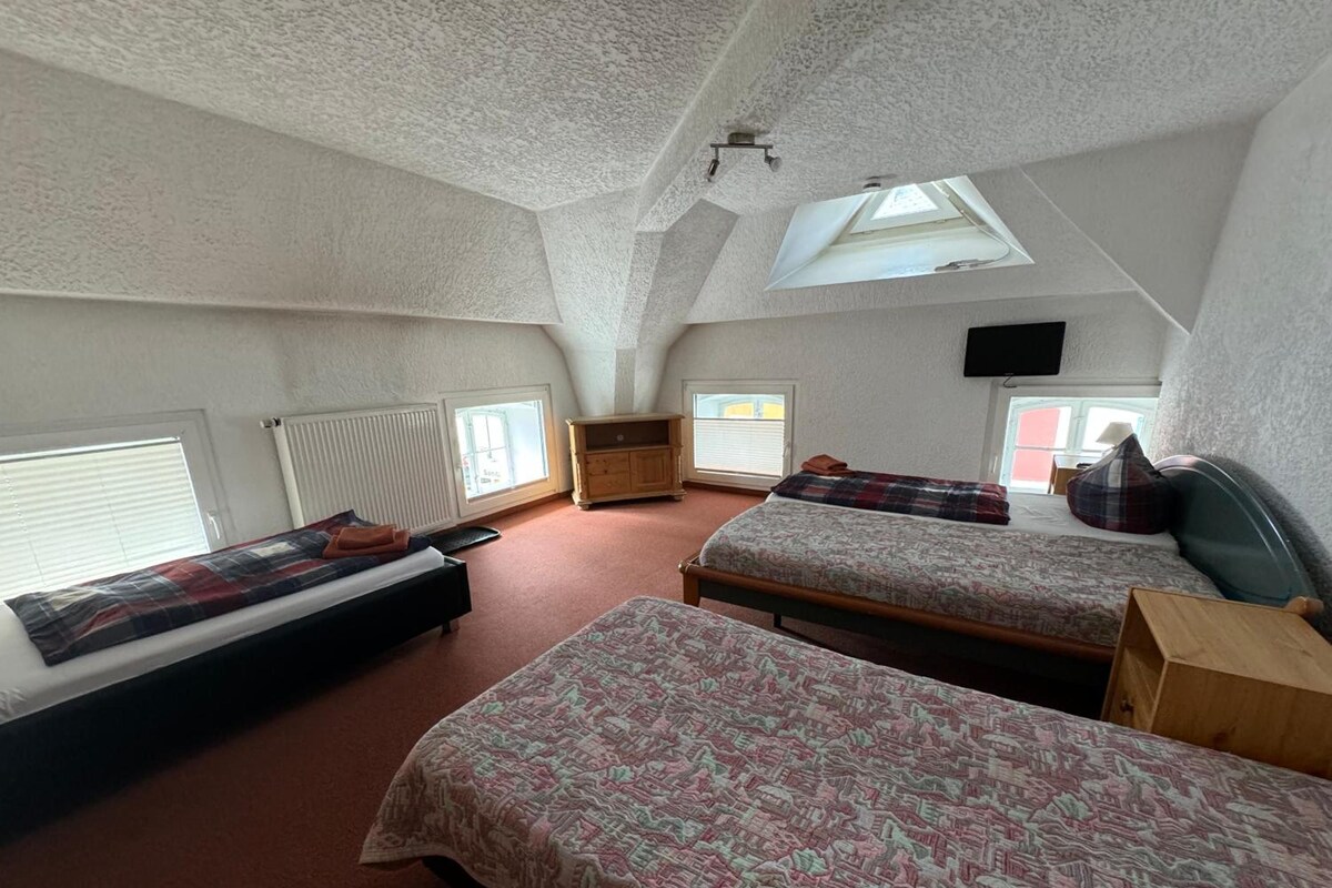 Un dormitorio con dos camas, un armario de madera, un radiador y un tragaluz.