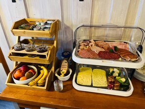 Un bufé con diversas opciones de comida, incluyendo frutas, carnes y salsas.