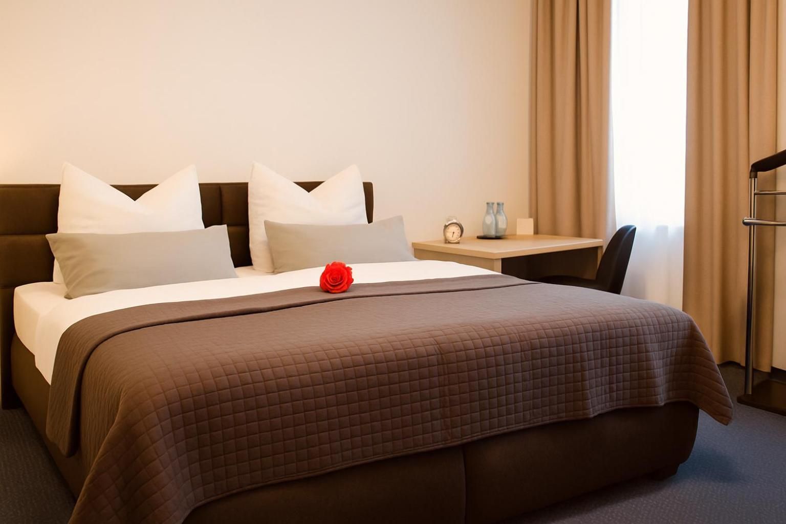 Ein Hotelzimmer mit einem Bett, einem Nachttisch mit Uhr und Vase sowie einem Sessel.