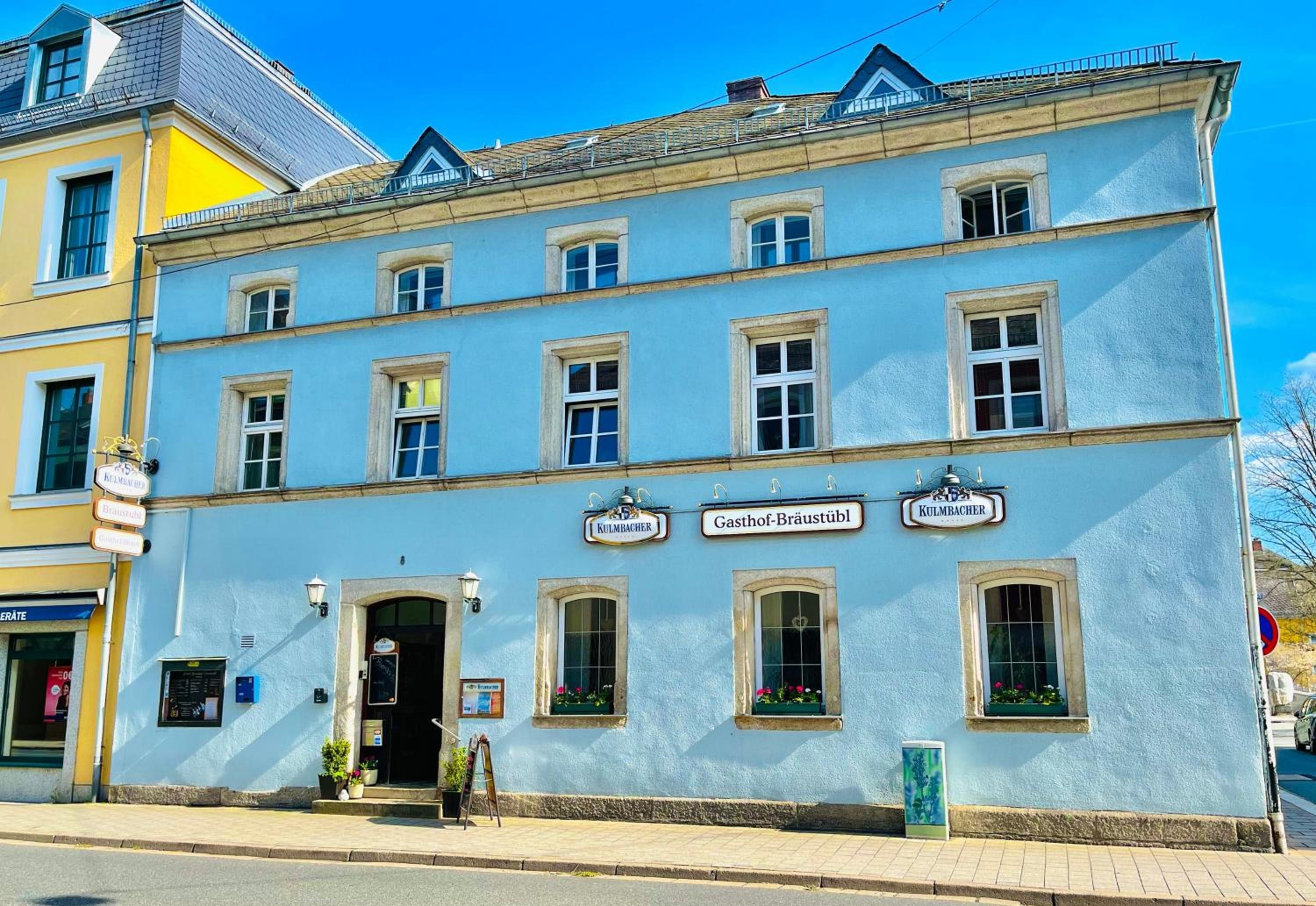 Ein zweistöckiges Gebäude mit blauer Fassade, zahlreichen Fenstern und Schildern, die es als Restaurant kennzeichnen.