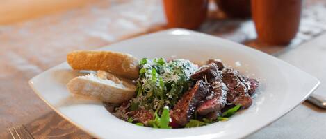 A plate of food with meat, greens, and bread on a table.
