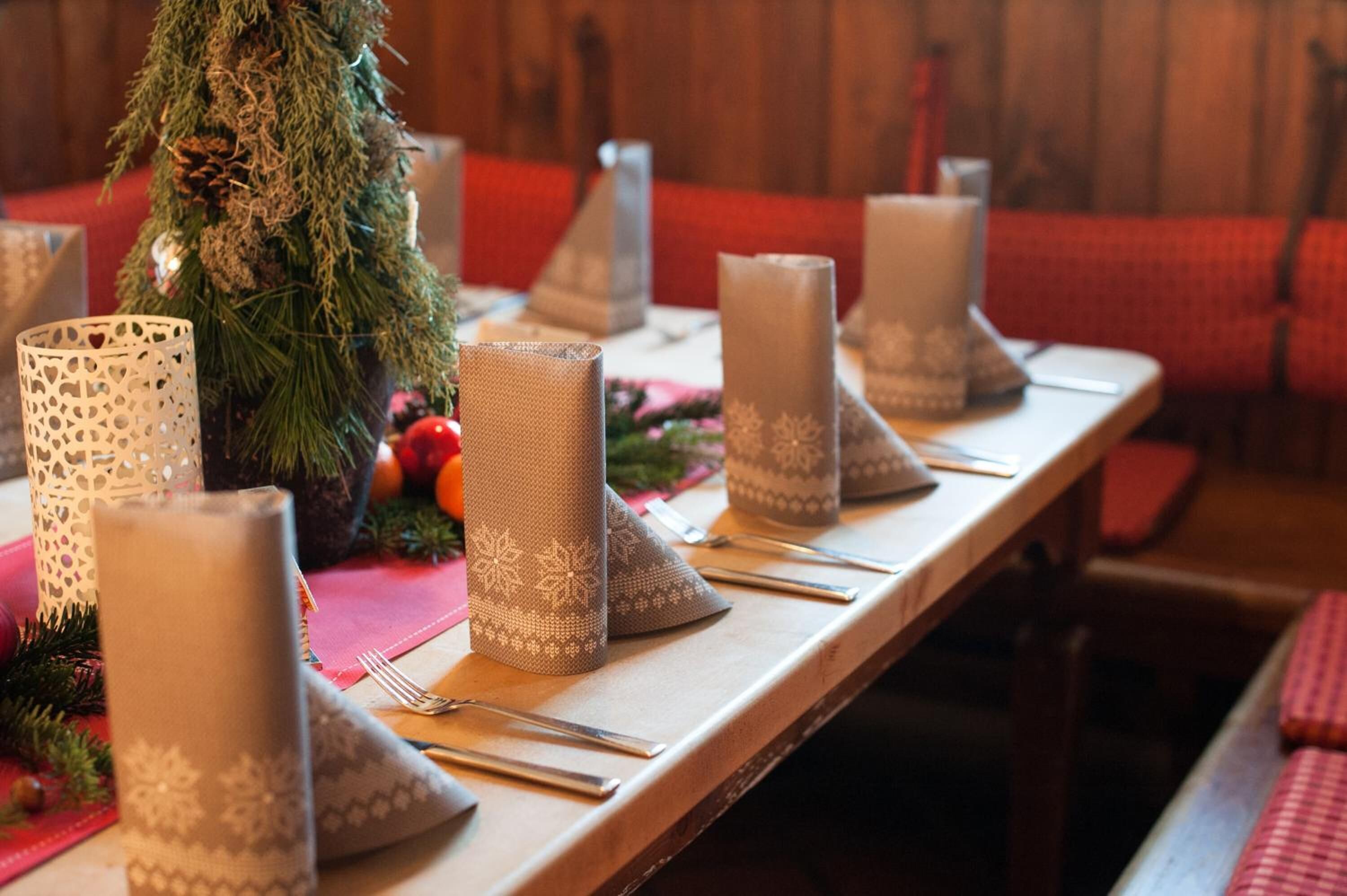 Ein gedeckter Tisch mit Kerzen, einem Weihnachtsbaum und festlicher Dekoration.