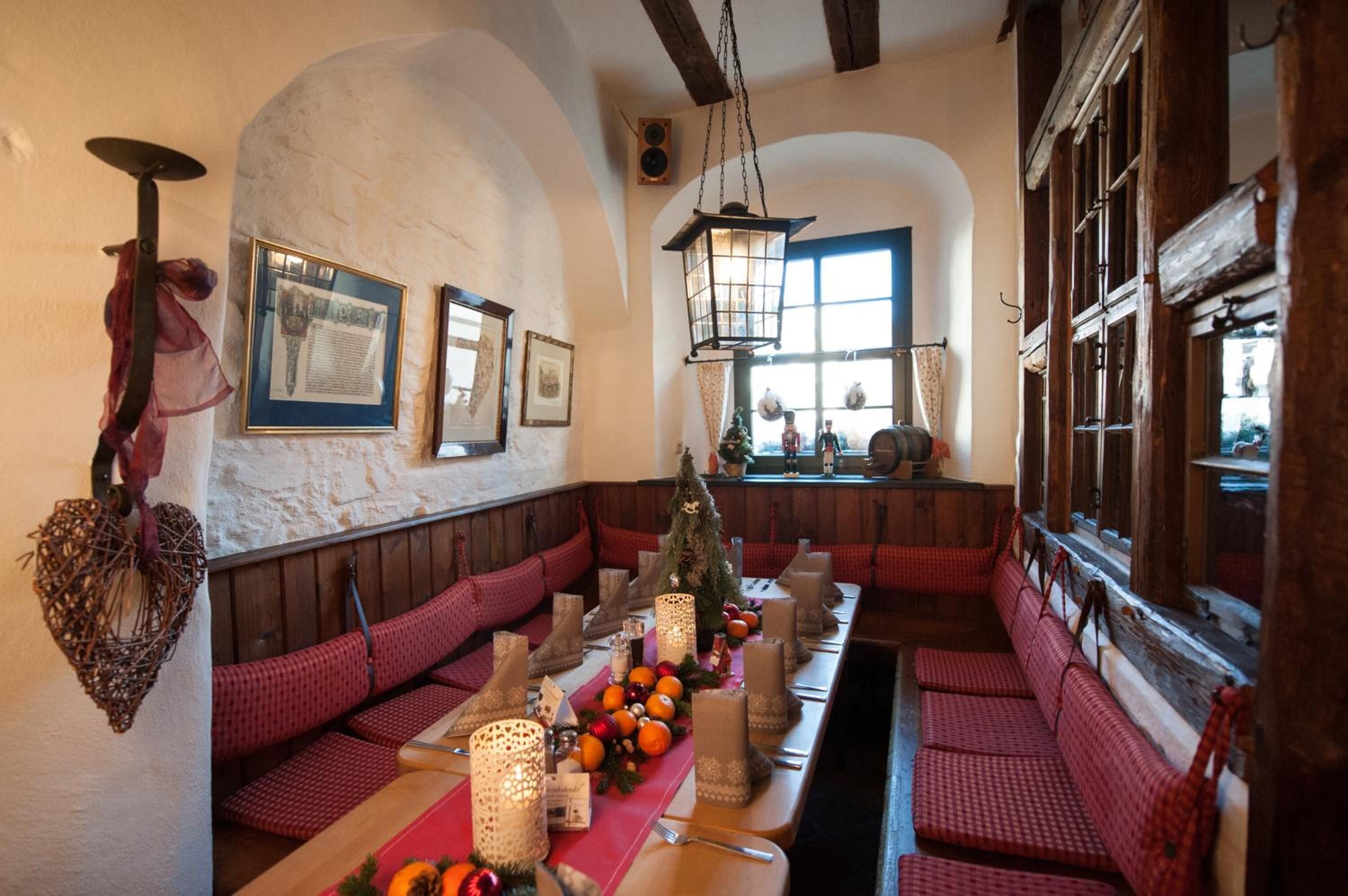 Un restaurante acogedor con bancos de madera y una mesa larga dispuesta para comer.