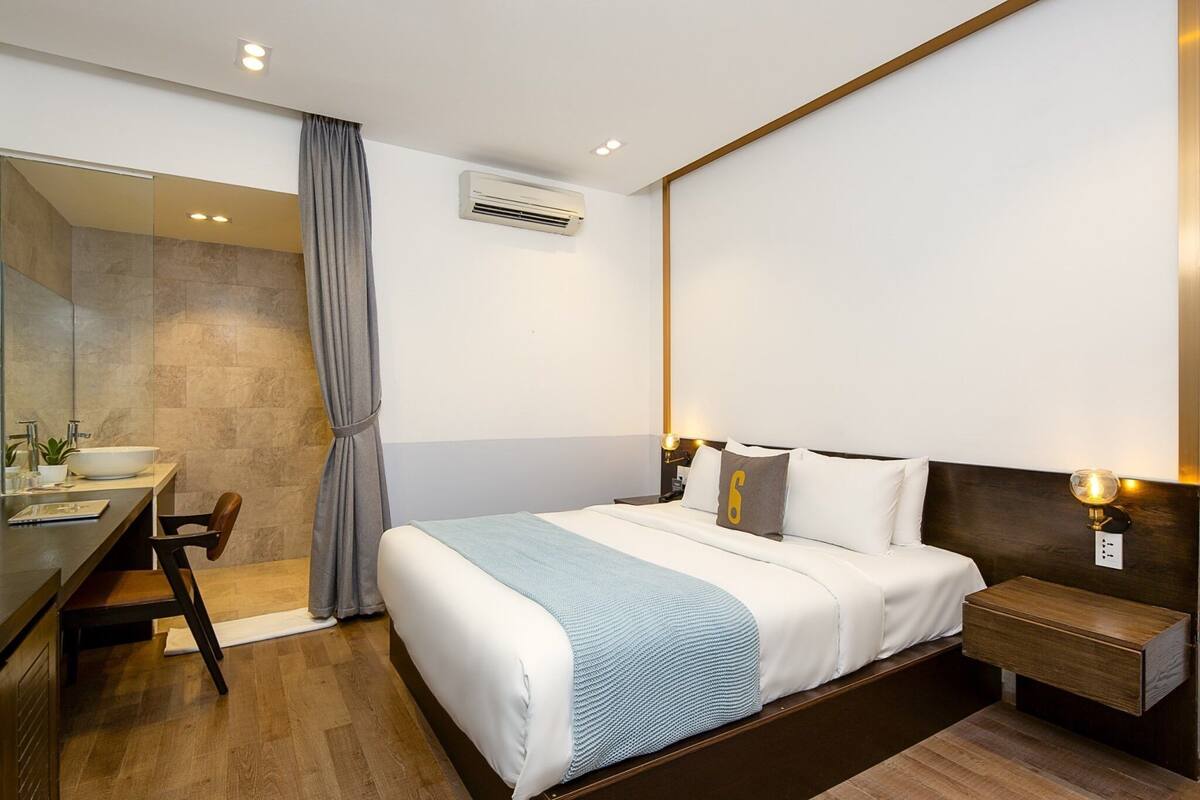 Una habitación de hotel moderna con una cama grande, una mesita de noche y un escritorio integrado con una silla.