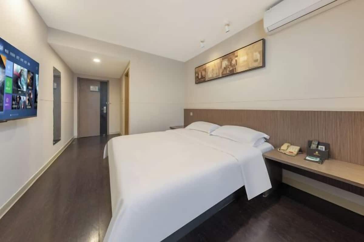 Une chambre d’hôtel avec un grand lit, un bureau avec un téléphone et une œuvre d’art accrochée au mur.