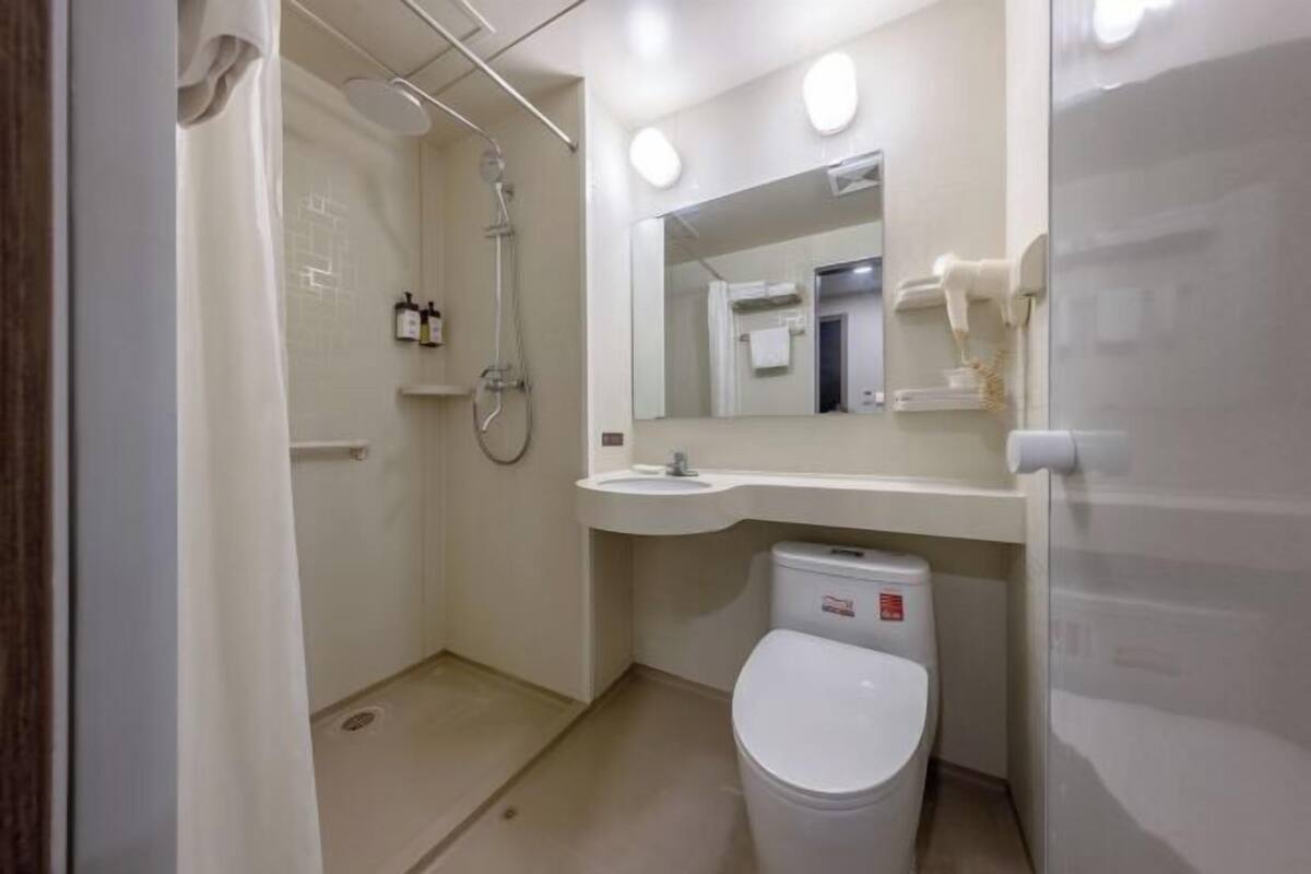 Une salle de bain équipée d’une douche, de toilettes, d’un lavabo et d’un miroir.