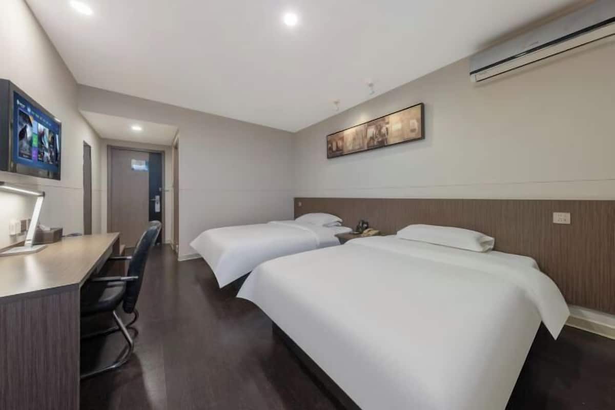 Une chambre d’hôtel avec deux lits, un bureau, une chaise, une télévision et la climatisation.
